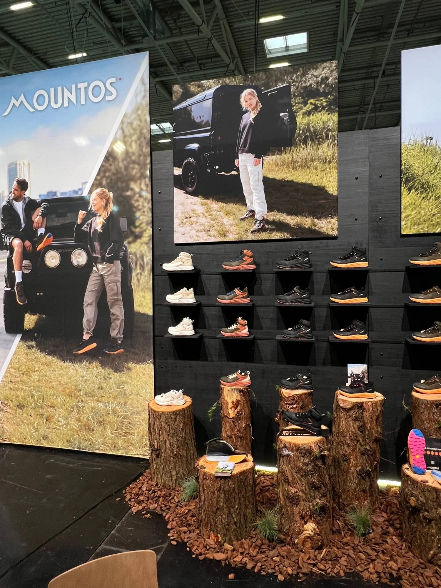 Outdoor kant van de Mountos-stand: schoenen op boomstronken in een bed van schors